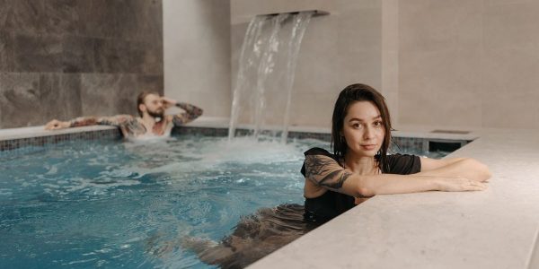 A couple enjoying a relaxing moment together in an indoor pool with a waterfall.
