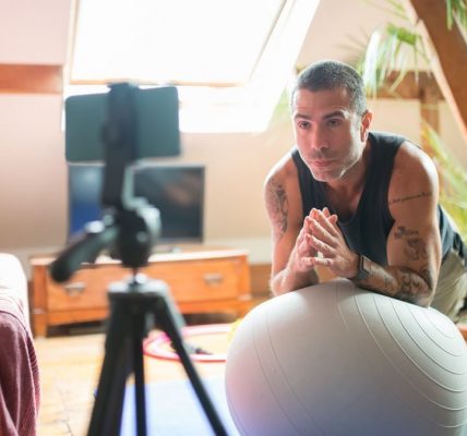 A man works out with a stability ball in a cozy home gym, recorded on a smartphone.