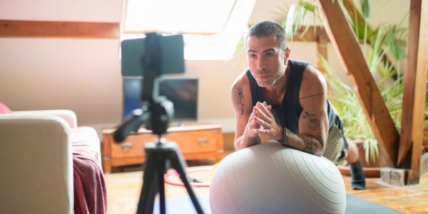 A man works out with a stability ball in a cozy home gym, recorded on a smartphone.